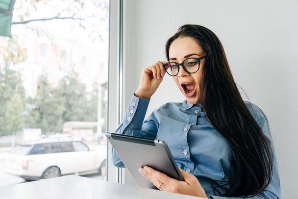 surprised happy business woman with glasses working on a tablet, freelancing - Foto, Imagem