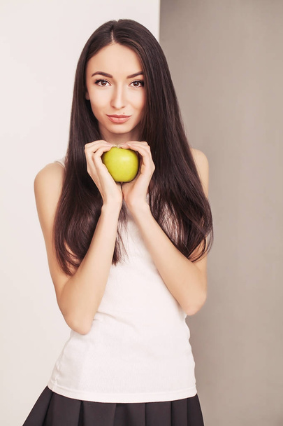 Δίαιτα. Μια νεαρή γυναίκα ρολόγια το σχήμα της και τρώγοντας φρέσκα φρούτα. Η έννοια της υγιεινής διατροφής. - Φωτογραφία, εικόνα