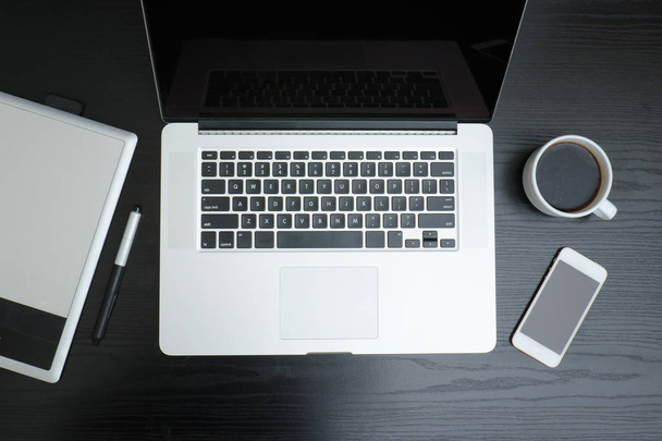 Open laptop, graphic tablet, smartphone and coffee mug - Fotó, kép