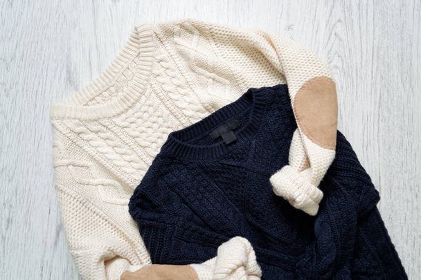 Два теплых вязаных свитера на деревянном фоне
 - Фото, изображение
