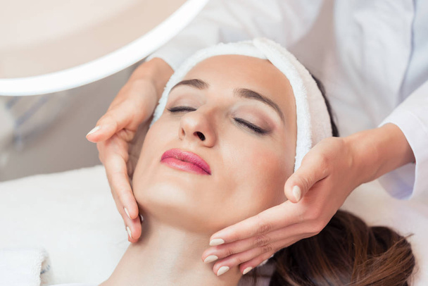 Mulher bonita relaxante durante a massagem facial para rejuvenescimento
 - Foto, Imagem