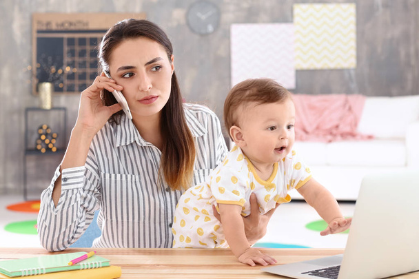 junge Mutter hält Baby während der Arbeit im Home Office - Foto, Bild