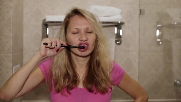 Young woman brushing her teeth in the bathroom. - Séquence, vidéo