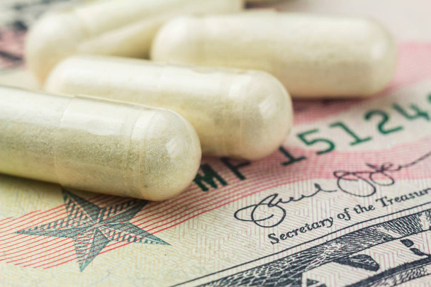 Cápsulas blancas de condroitina de glucosamina, píldoras de suplementos saludables en billetes de dólar, imagen macro
. - Foto, Imagen