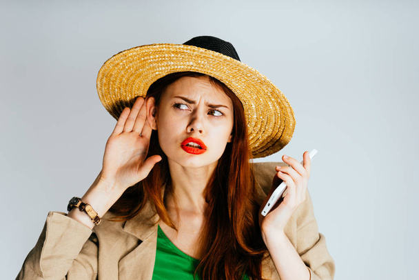 a girl in a big hat is holding a mobile phone and listening to sounds, isolated - Foto, immagini