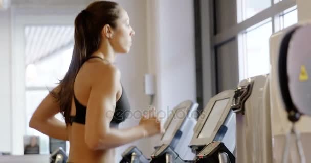 Fit woman in workout clothes running on treadmill machine in fitness gym - Кадры, видео