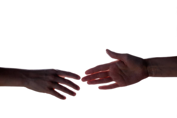 Geïsoleerde afbeelding van een silhouet van de jongen handen voor de vrouw hand te bereiken. Handen van moeder en zoon. Het concept van de familie, hulp, ondersteuning en liefde. - Foto, afbeelding