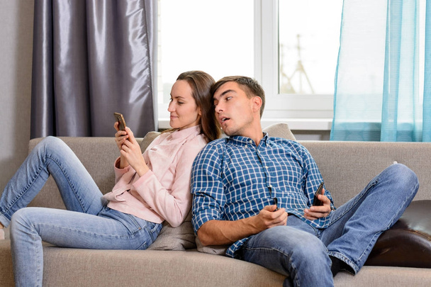 A fiatal férfi kémkedés barátnők telefon részére társadalmi hálózat és kommunikáció - Fotó, kép