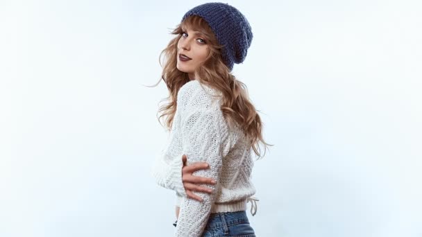 Retrato de sensual mujer rubia positiva hermosa en suéter y sombrero azul aislado sobre fondo blanco en estudio
 - Imágenes, Vídeo