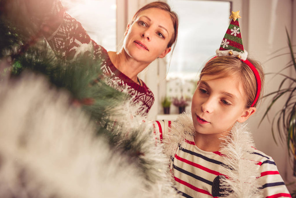 Mother and daughter decorating christmas tree - Фото, зображення