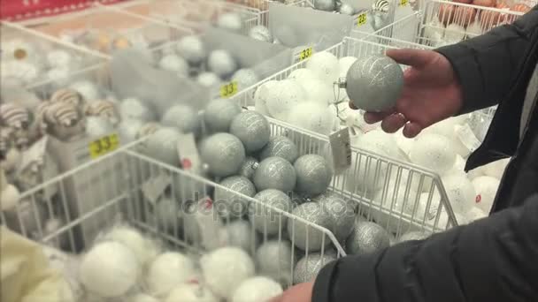 Mans hands are touching balls for decorating Xmas and new year trees in a shop - Footage, Video