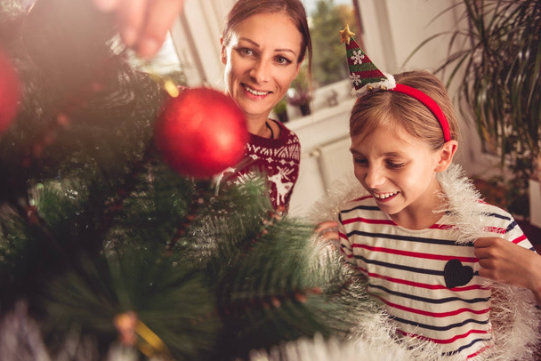 Mother and daughter decorating christmas tree - Valokuva, kuva
