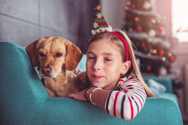Little girl with dog posing on sofa   - Фото, зображення