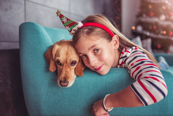 Little girl with dog posing on sofa - Фото, изображение