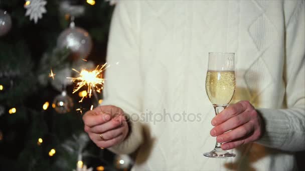 Мужчина держит в руках искру и бокал шампанского на празднике Нового года
 - Кадры, видео