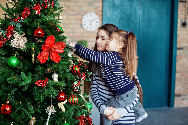 Μικρή αδελφή διακόσμησης ενός χριστουγεννιάτικου δέντρου.  - Φωτογραφία, εικόνα