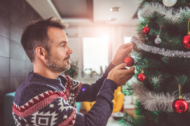 Man decorating Christmas tree - Foto, imagen