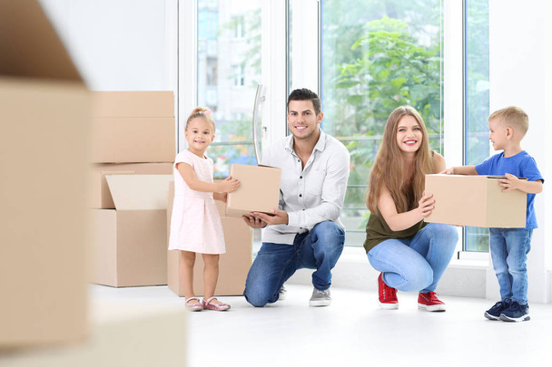 Happy family with moving boxes in their new house - Fotoğraf, Görsel
