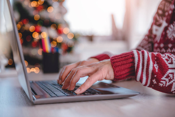 Woman wearing red sweater using laptop at home during christmas - Φωτογραφία, εικόνα
