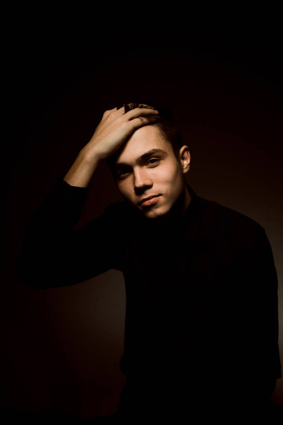 young guy on a dark studio background - Фото, изображение