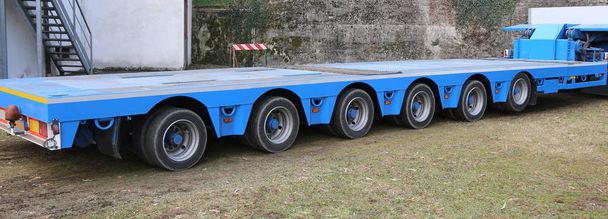 очень длинный синий грузовик с шестью осями колес
 - Фото, изображение
