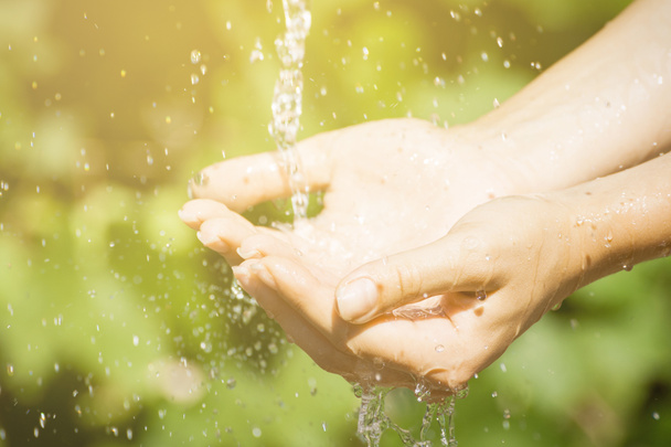 Vrouw wassen hand buitenshuis. Natuurlijke drinkwater in de palm. Jonge handen met water splash, selectieve aandacht - Foto, afbeelding
