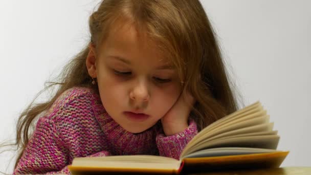 Jeune fille souriant tout en lisant le livre. Vue de face de mignon adolescent couché avec livre ouvert
. - Séquence, vidéo