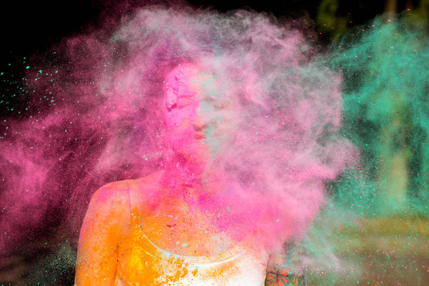 Young woman posing with exploding  pink and green Holi powder ar - Photo, Image