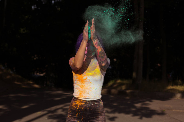 Ένδοξη γυναίκα με μωβ μαλλιά πετώντας μέχρι πολύχρωμα σκόνη Holi  - Φωτογραφία, εικόνα