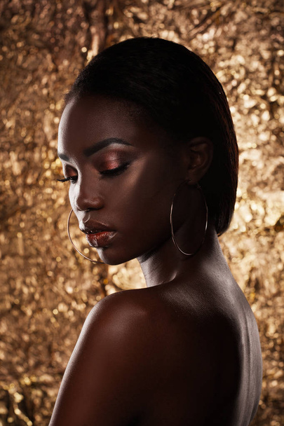 Fashion studio portrait of an extraordinary beautiful african american model with closed eyes  over golden background - Foto, immagini