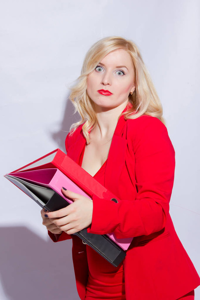 Portrait of a beautiful young blonde woman in a red business suit. The girl holds a folder for documents - Fotografie, Obrázek