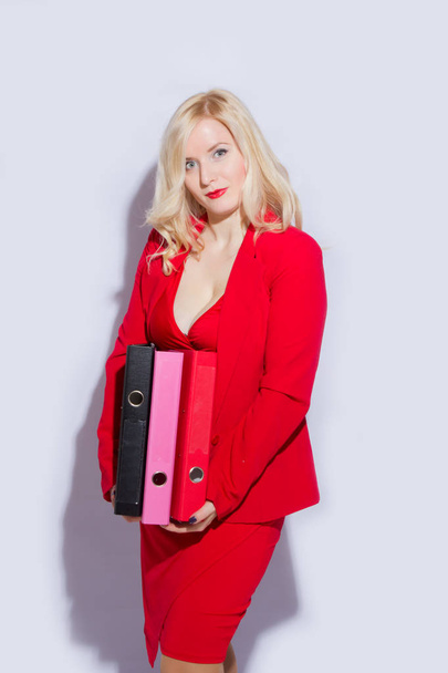 Portrait of a beautiful young blonde woman in a red business suit. The girl holds a folder for documents - Foto, immagini