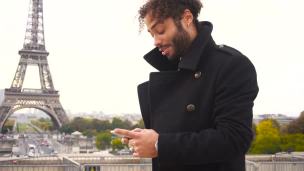 ausländischer Freund chattet mit französischem Mädchen auf Smartphone um den Eiffelturm in Zeitlupe. - Filmmaterial, Video