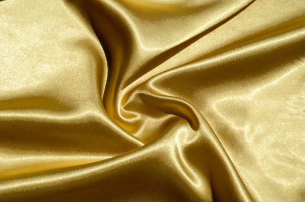 Tekstuuri, kangas, tausta. Abstrakti tausta ylellinen kangas tai nestemäisten aaltojen tai aaltoileva grunge prässi silkki satiini tekstuuri sametti materiaalia tai ylellinen joulu tai tyylikäs tausta. kulta
 - Valokuva, kuva