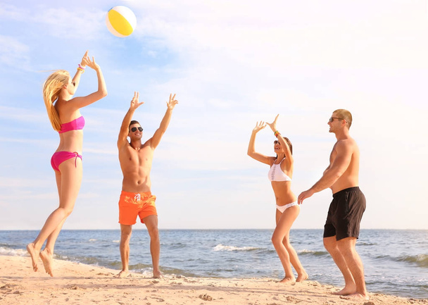Group of young people playing volleyball on beach - 写真・画像