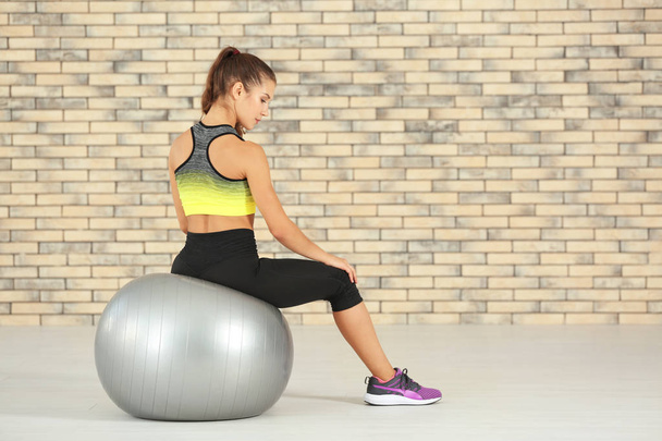 Sporty young woman sitting on fitball at home - Φωτογραφία, εικόνα