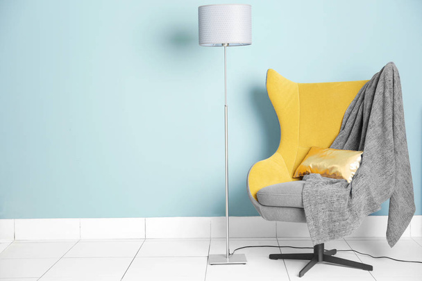 Comfortable armchair and lamp on blue wall background - Photo, Image