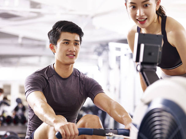 young asian couple working out using rowing machine - Photo, Image