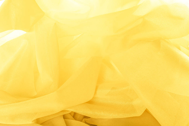 Tekstuuri, tausta, kuvio. Silkkikankaan rakenne on keltainen. Silkki kangas on läpinäkyvä
. - Valokuva, kuva