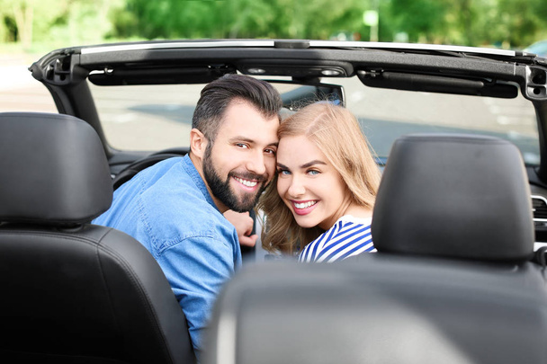 Happy young couple sitting in car - Fotó, kép