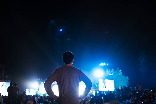 um homem com pessoas lotadas desfrutando de festival de música noturna ao ar livre
 - Foto, Imagem