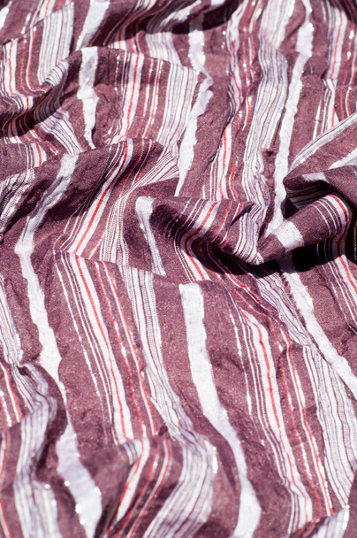 Textúra, háttér, minta. Női csíkos sál, barna csíkos ruha, fehér, piros, csillogó - Fotó, kép