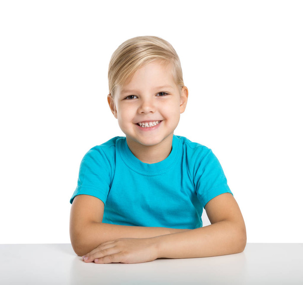 boldog kis lány ül egy asztalnál, és mosoly - Fotó, kép