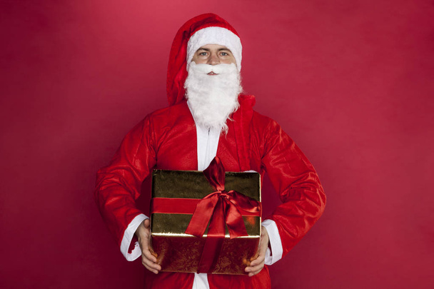 Santa Claus κρατά ένα όμορφα τυλιγμένο δώρο - Φωτογραφία, εικόνα