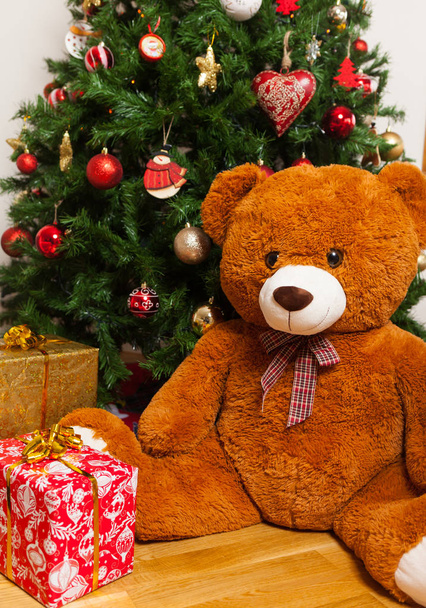 Teddy bear near christmas tree with gifts - Foto, afbeelding