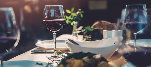 Glass of red wine at dining table in backyard patio  - 写真・画像
