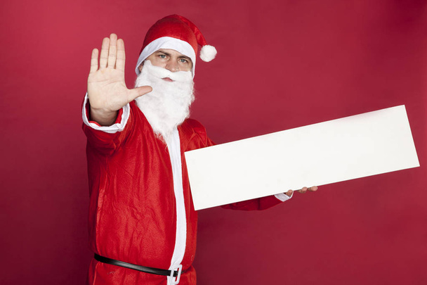 Santa Claus performs a stop gesture, advertising in his hand - Photo, Image