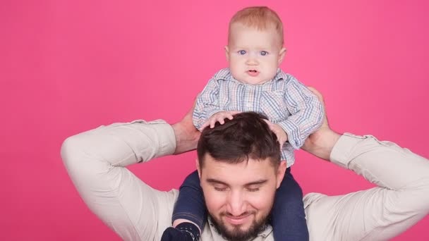 Pai com pequeno filho bonito sobre fundo rosa
 - Filmagem, Vídeo