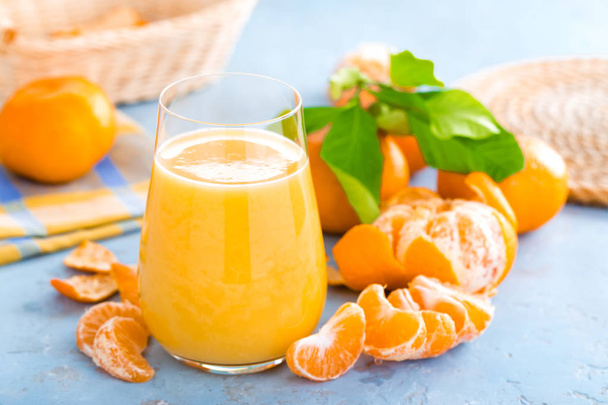 Tangerines, peeled tangerines and tangerine juice in glass. Mandarine juice and fresh fruits with leaves. - Valokuva, kuva