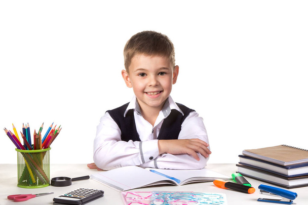 Χαμογελώντας χαρούμενα άριστος μαθητής κάθεται ακόμα στο γραφείο με λευκό φόντο - Φωτογραφία, εικόνα
